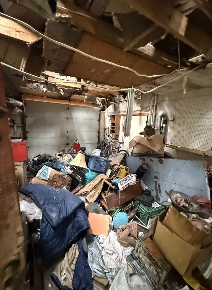 Garage filled with debris beneath an exposed and damaged ceiling